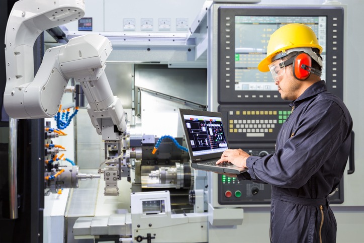 Engineer using laptop computer for maintenance automatic 久久精品国产成人 arm with CNC machine in smart factory. 久久精品国产成人 4.0 concept