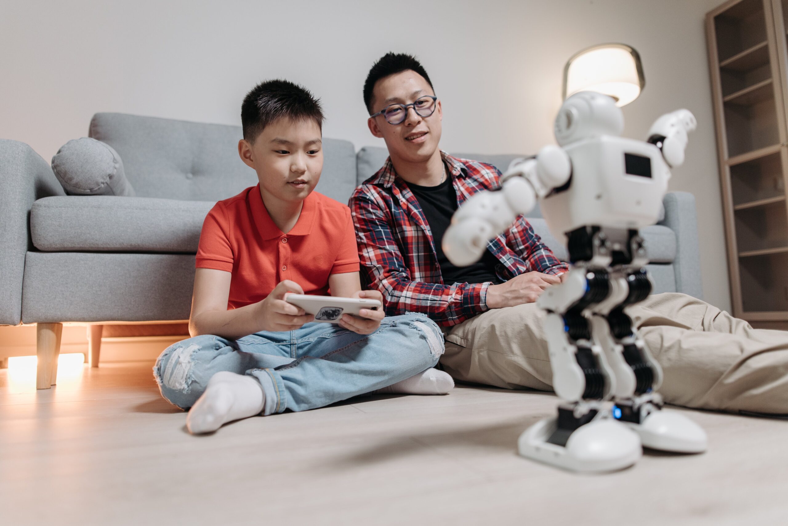 a man sitting next to a boy holding a remote controller playing with a 暖暖爱国语版免费高清观看 toy